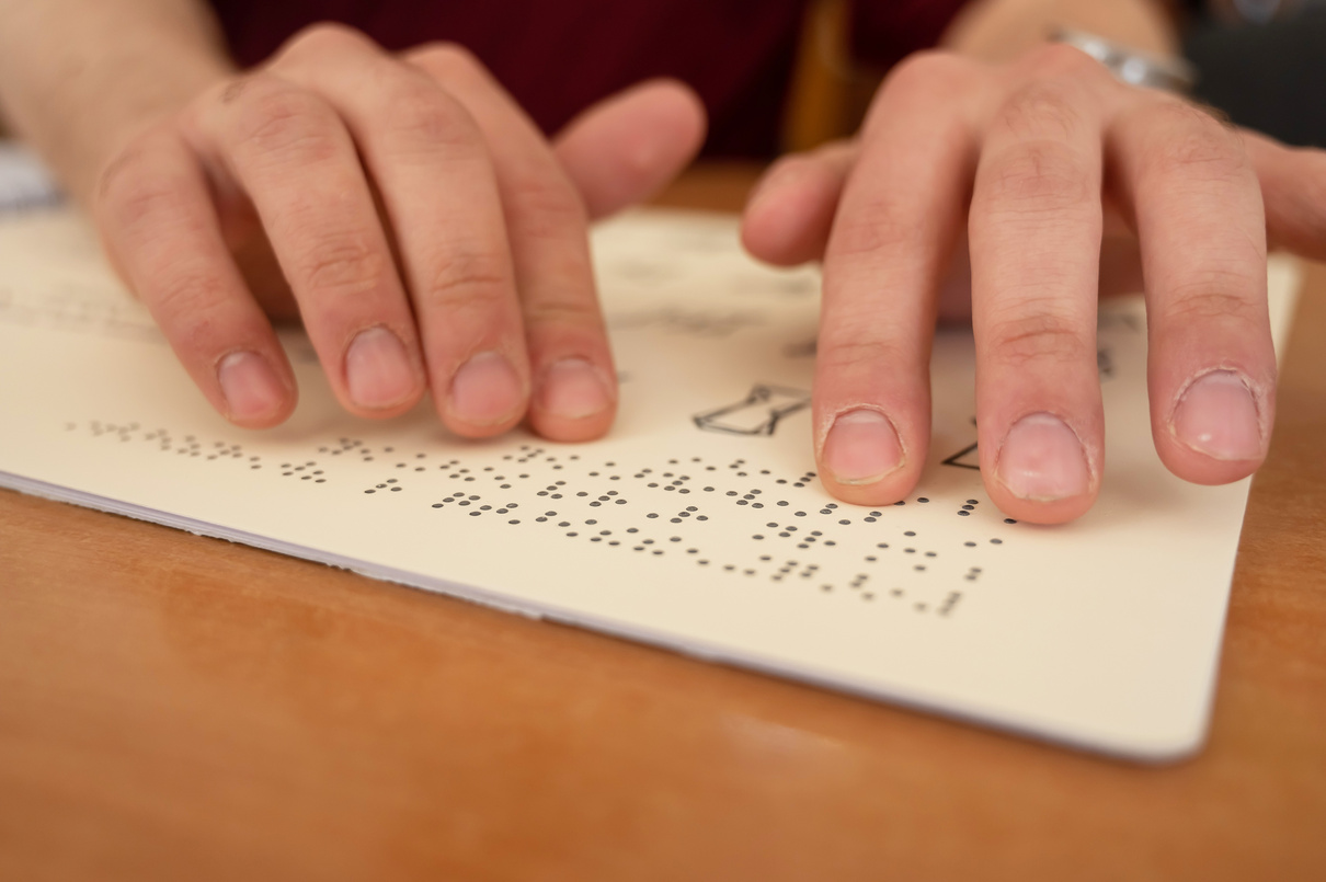 Visually impaired man reading a braille book.